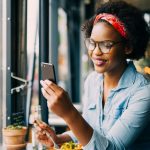 Smiling woman reading text messages over dinner in a bistro