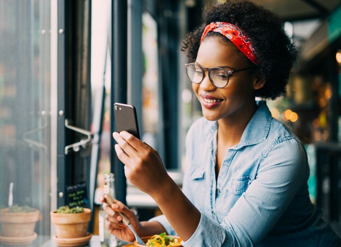 Smiling woman reading text messages over dinner in a bistro